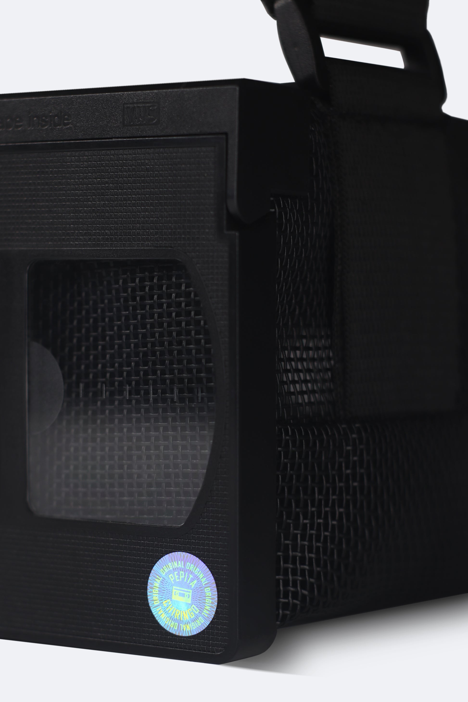 Close-up of the front detail of the black VHS handbag from the Videoclub 2025 Collection by Pepita Chiringo, showcasing the holographic sticker label, reminiscent of classic VHS tapes, adding a nostalgic touch to this handmade, sustainable fashion accessory.